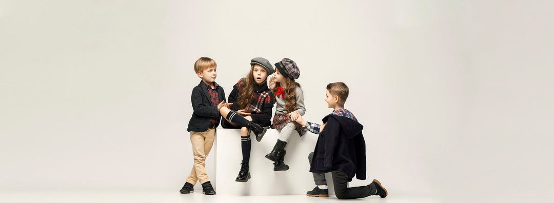 Four children in stylish winter clothing posing together on a white background