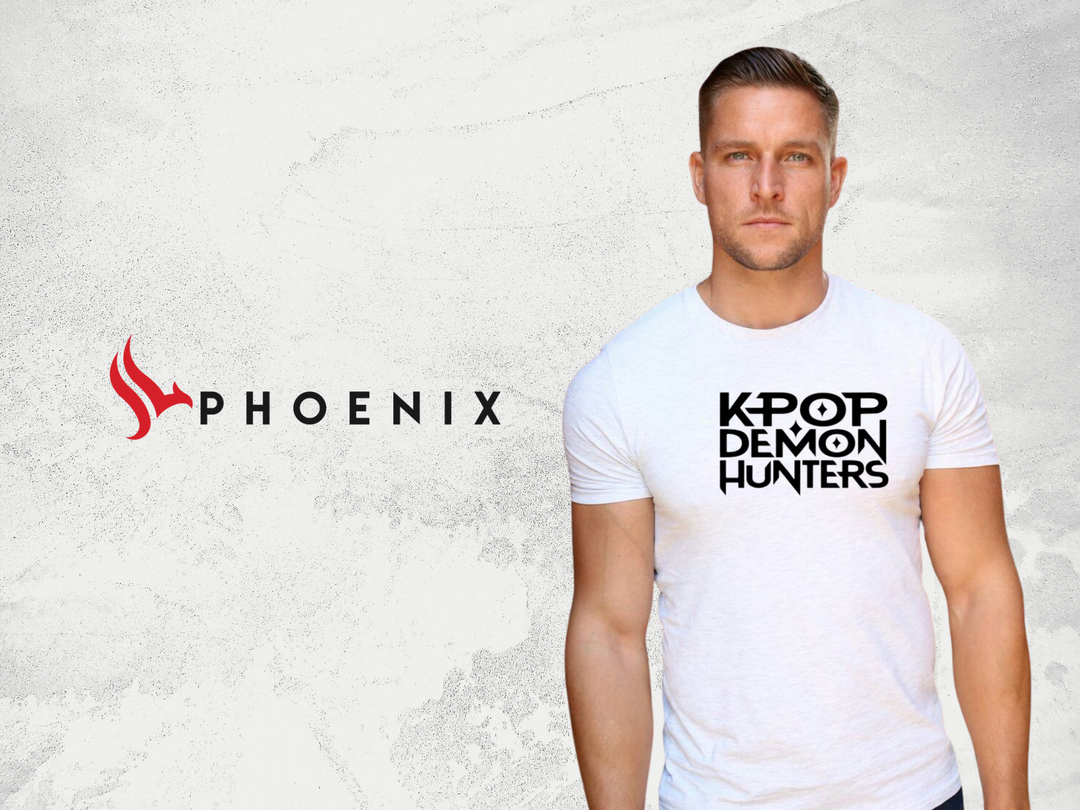 Man in white KPOP DEMON HUNTERS graphic t-shirt, standing on light textured background, PHOENIX logo on left.