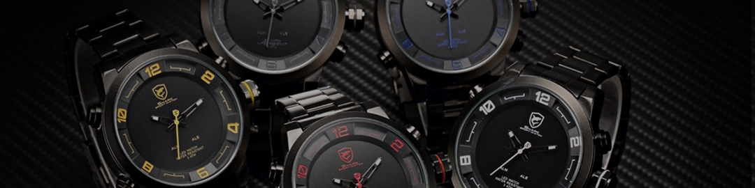 Five black stainless steel men's wristwatches with bold colored accents on a carbon fiber surface