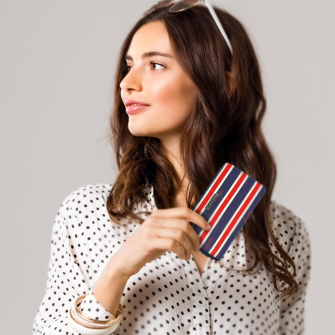 Woman holding a striped wallet against a plain background